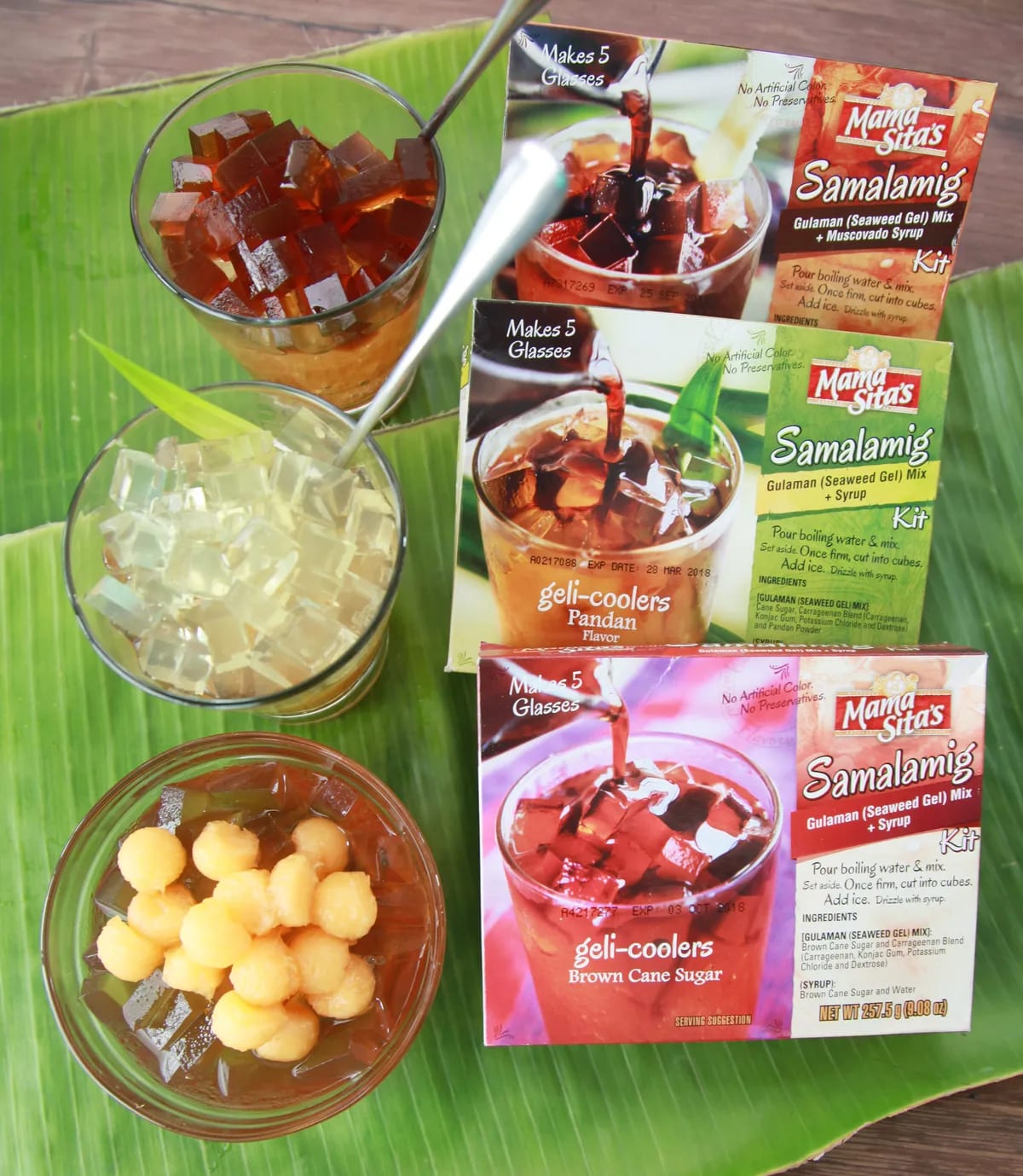Three Mama Sita’s Samalamig gulaman kits laid on a banana leaf beside glasses of gulaman and sago